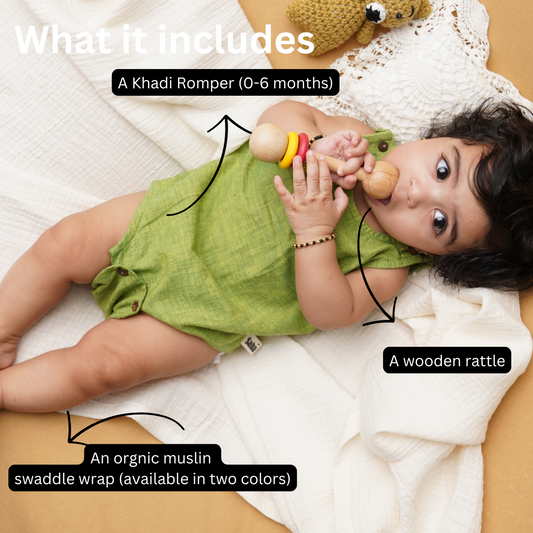 Baby in a green Khadi romper with a wooden rattle, lying on a Beige muslin swaddle wrap.