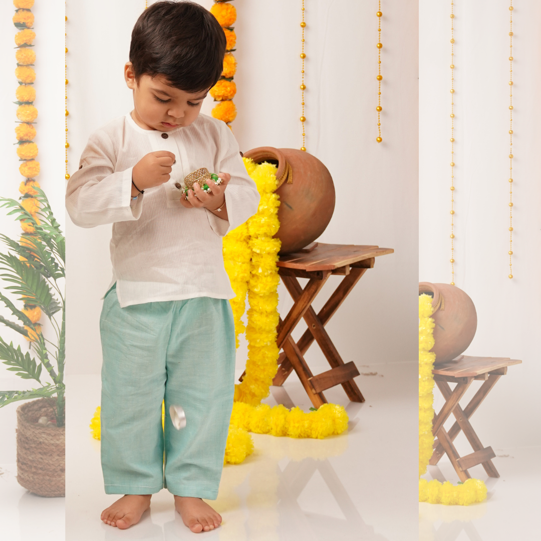 Child wearing khadi kurta and pants playing with toys in a decorated room with yellow ribbons and plants.