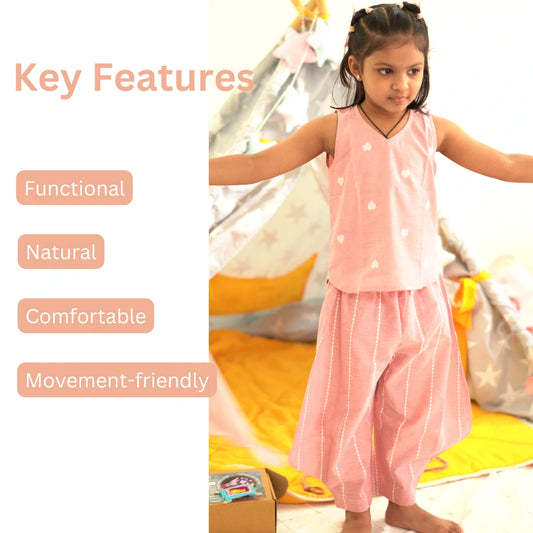 Toddler girl playing in a soft pink cotton coord set with text highlighting functional, natural, comfortable, and movement-friendly features
