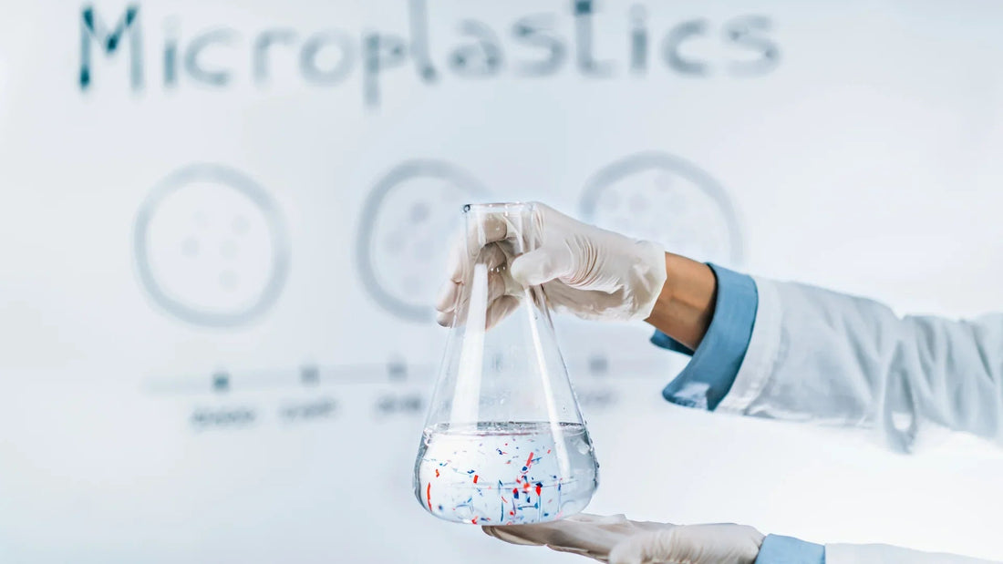 Scientist holding flask with water and microplastics, laboratory research on plastic pollution