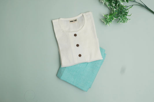 Folded white cotton kurta with brown buttons and blue pants, kids khadi clothes on pastel background