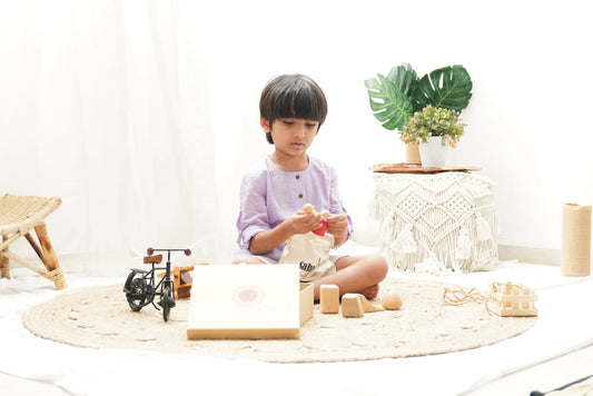 Child in pastel shirt playing with wooden Montessori toys on a round woven rug in a bright room