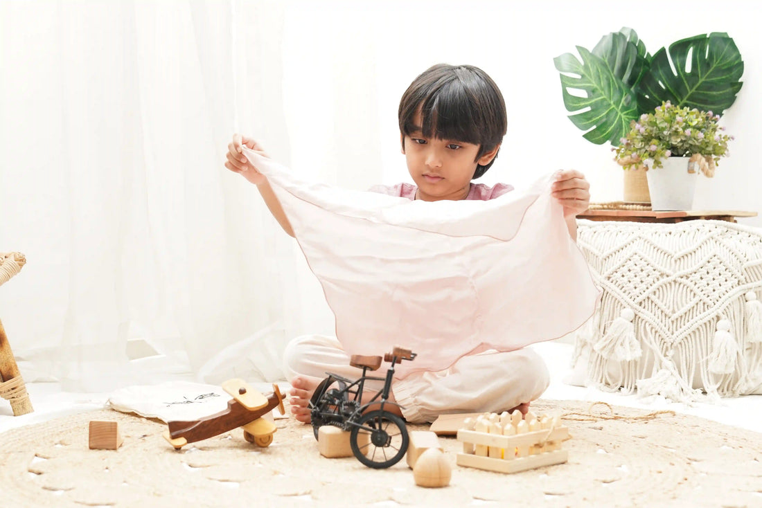 Child playing with open-ended wooden toys and fabric in a bright, cozy room