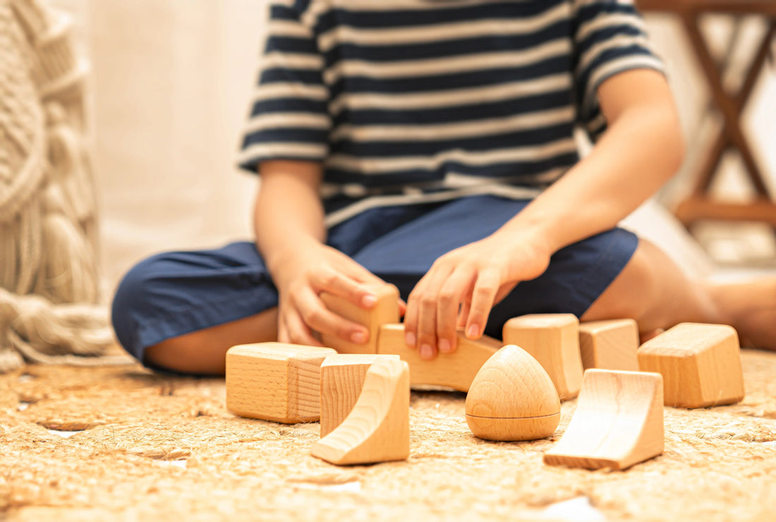 Child playing with natural wooden building blocks on a textured rug
