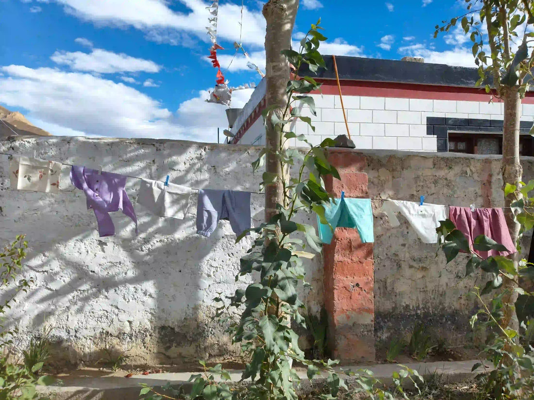 Organic cotton baby clothes and khadi kids outfits drying on a clothesline outdoors