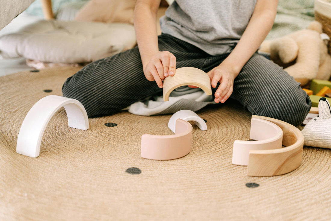 Child playing with open-ended wooden Montessori toys on a woven rug indoors