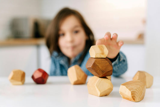 Child playing with open-ended wooden educational toys, natural stacking blocks on table