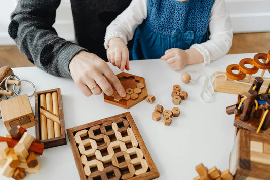 Adult and child playing with Montessori wooden educational toys and puzzles on a table