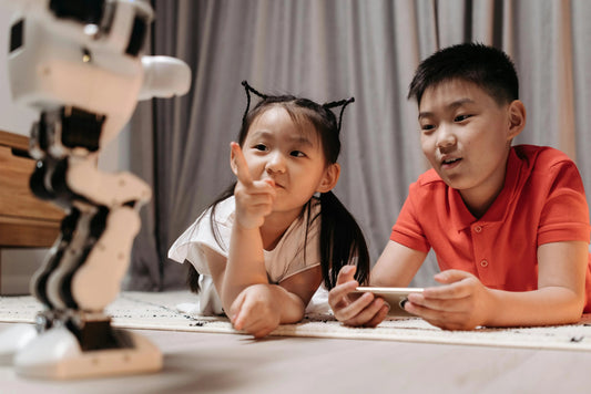 Children playing with educational robot toy indoors, girl pointing, boy holding remote