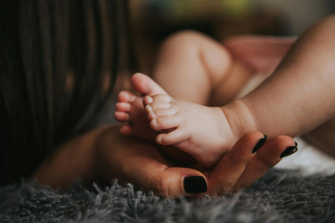 Close-up of a baby’s feet cradled in an adult hand, newborn care and bonding.