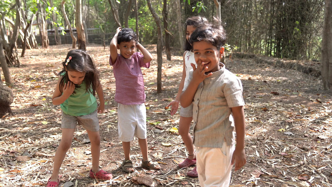 Children in organic cotton khadi clothes playing outdoors among trees, sustainable kids fashion