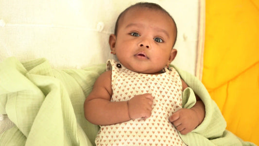 baby wearing cotton romper wrapped in muslin swaddles