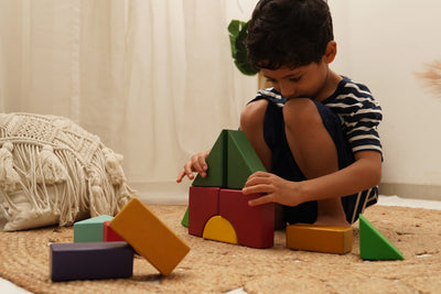 Child playing with colorful wooden building blocks on a woven rug, educational toys
