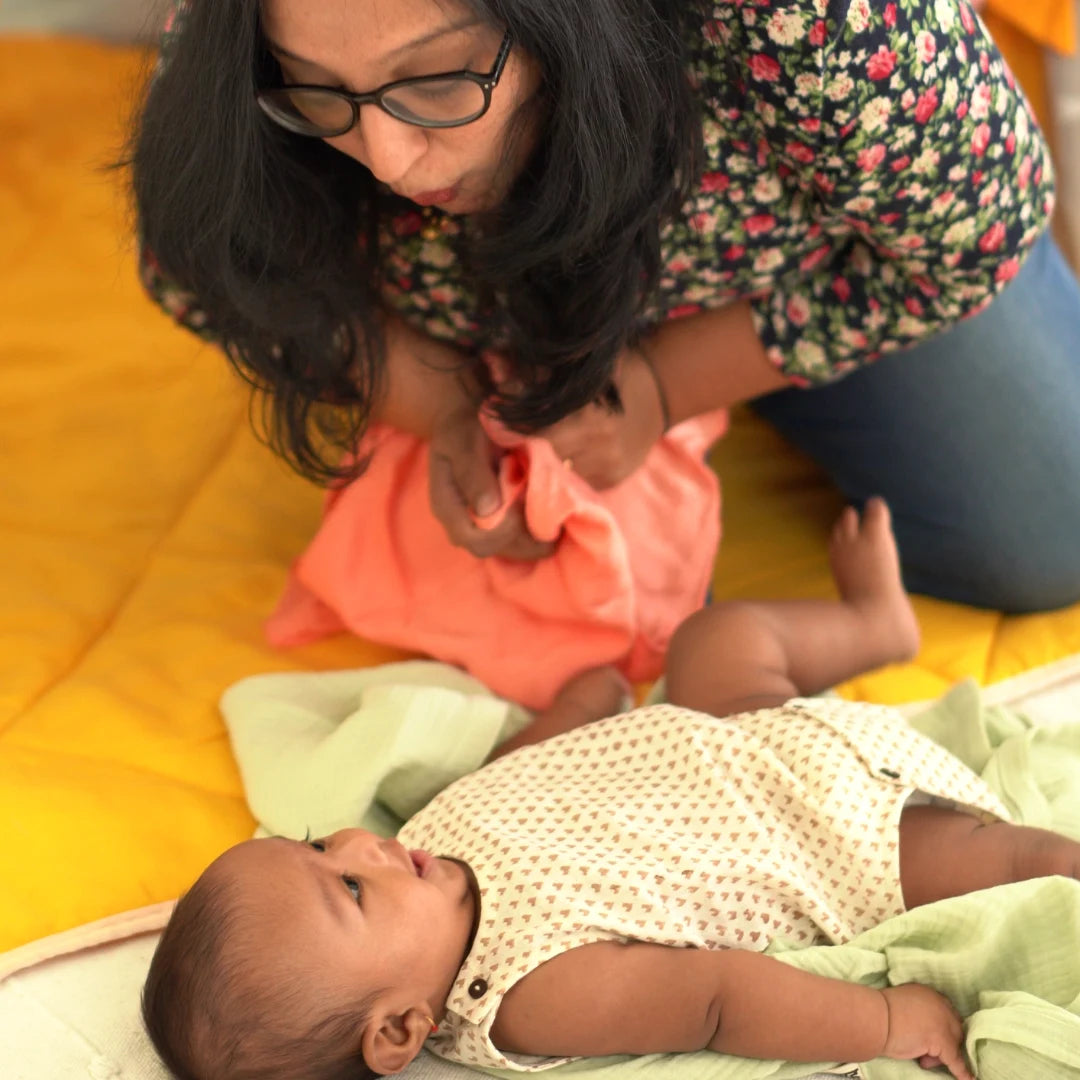 Mother interacting with her baby on a yellow blanket