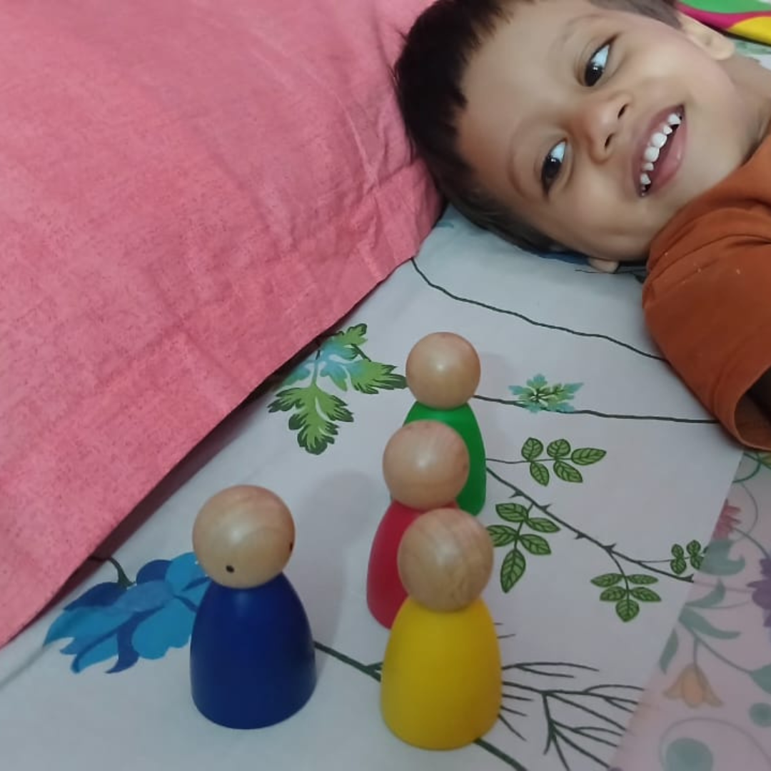 Boy playing with wooden peg dolls from Saha