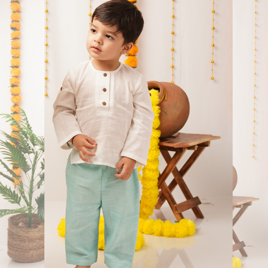 Child wearing a white shirt and light blue pants standing in a decorated room with yellow decorations and a wooden stool.