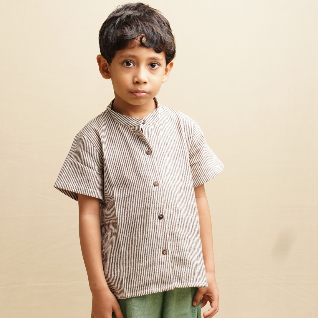 Boy wearing stripe shirt in pure cotton standing against a beige background