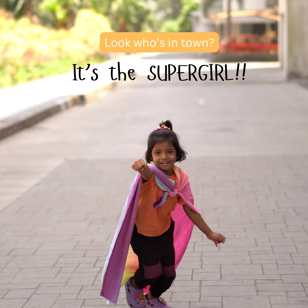 Child wearing a soft rainbow semi-giant playsilk as a superhero cape during imaginative outdoor play