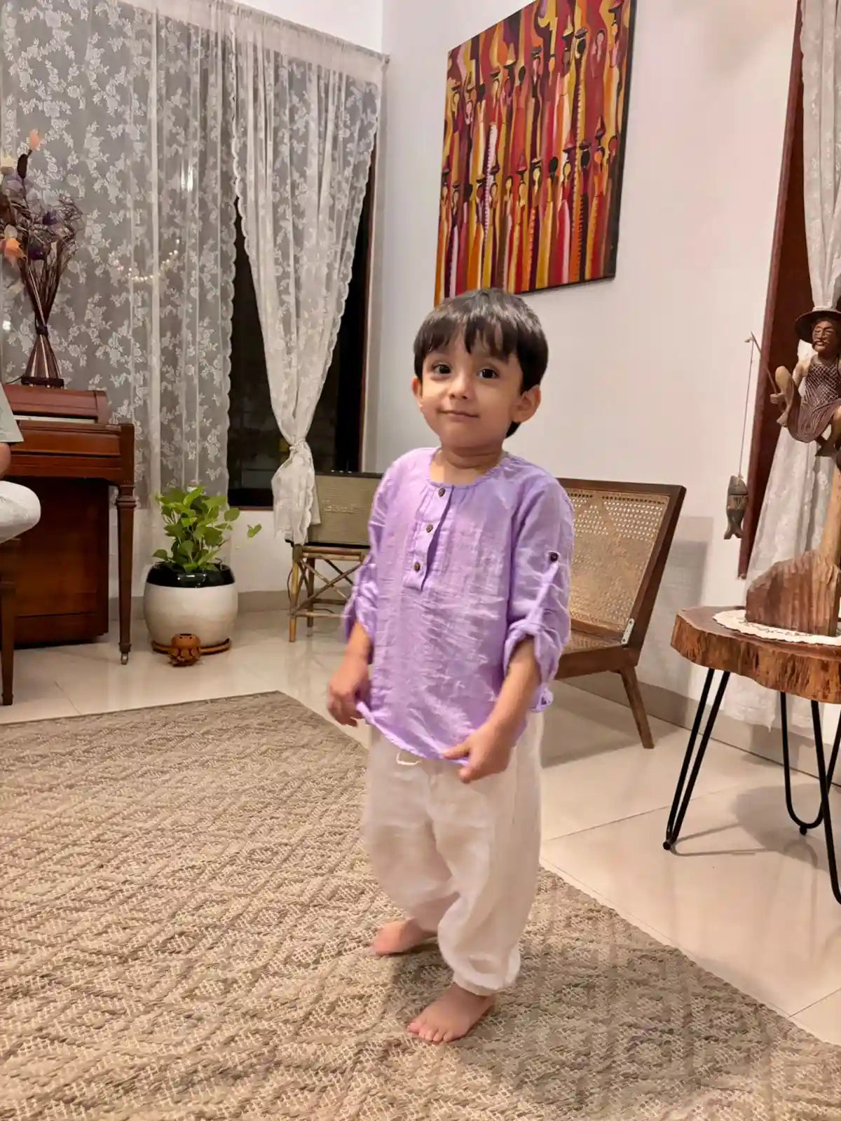 Child wearing purple shirt in pure cotton standing in a living room 