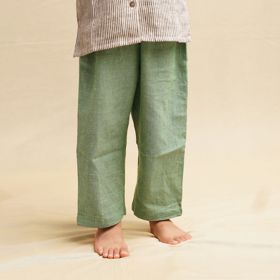 Green pants worn by a child on a beige background