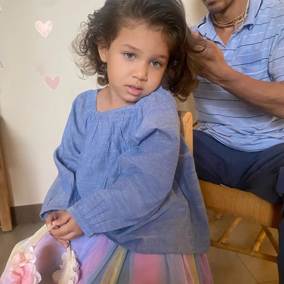Child in a blue cotton top getting ready