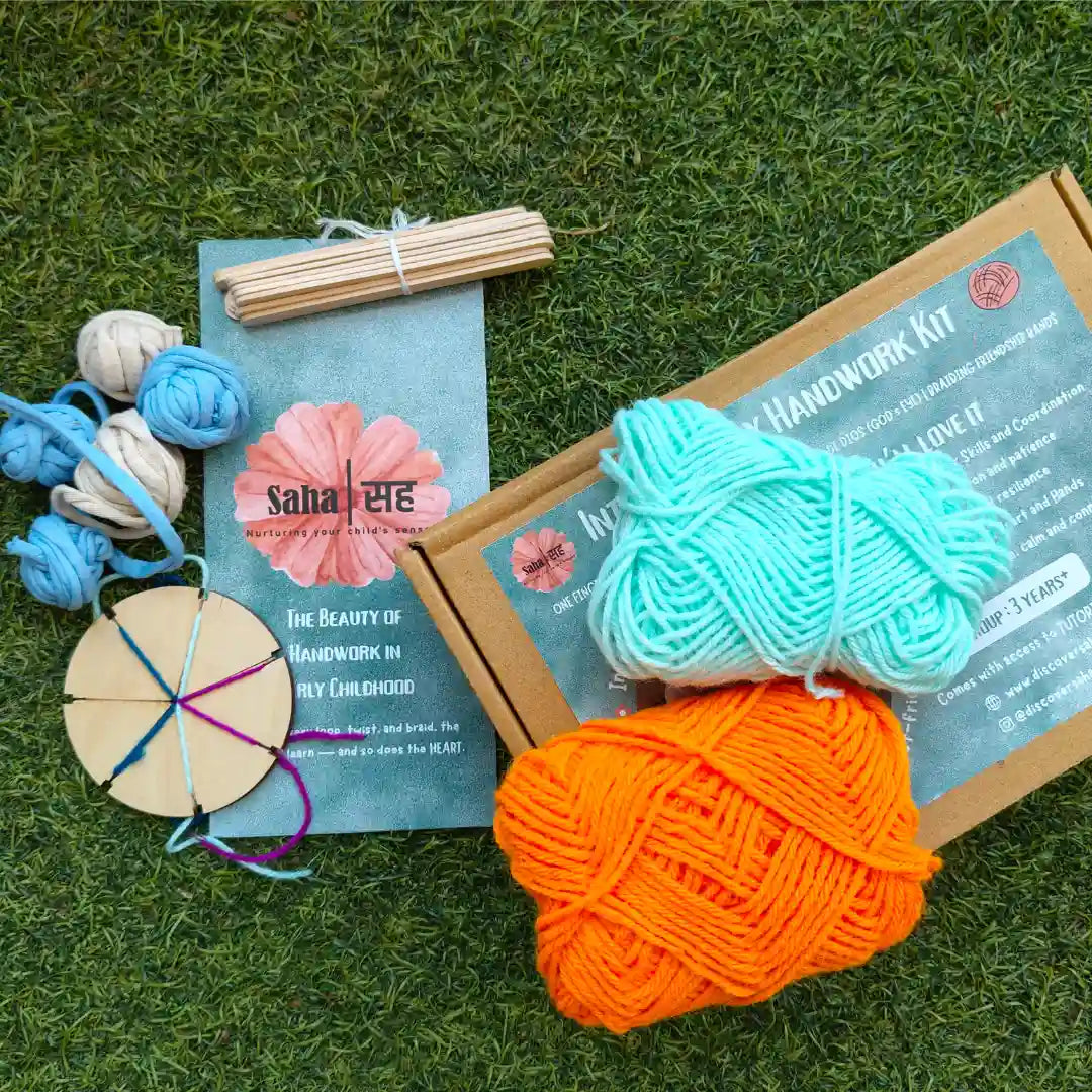 Introductory Handwork Activity Kit with wooden braiding disc, colorful yarn balls, weaving sticks, and handwork brochure on grass