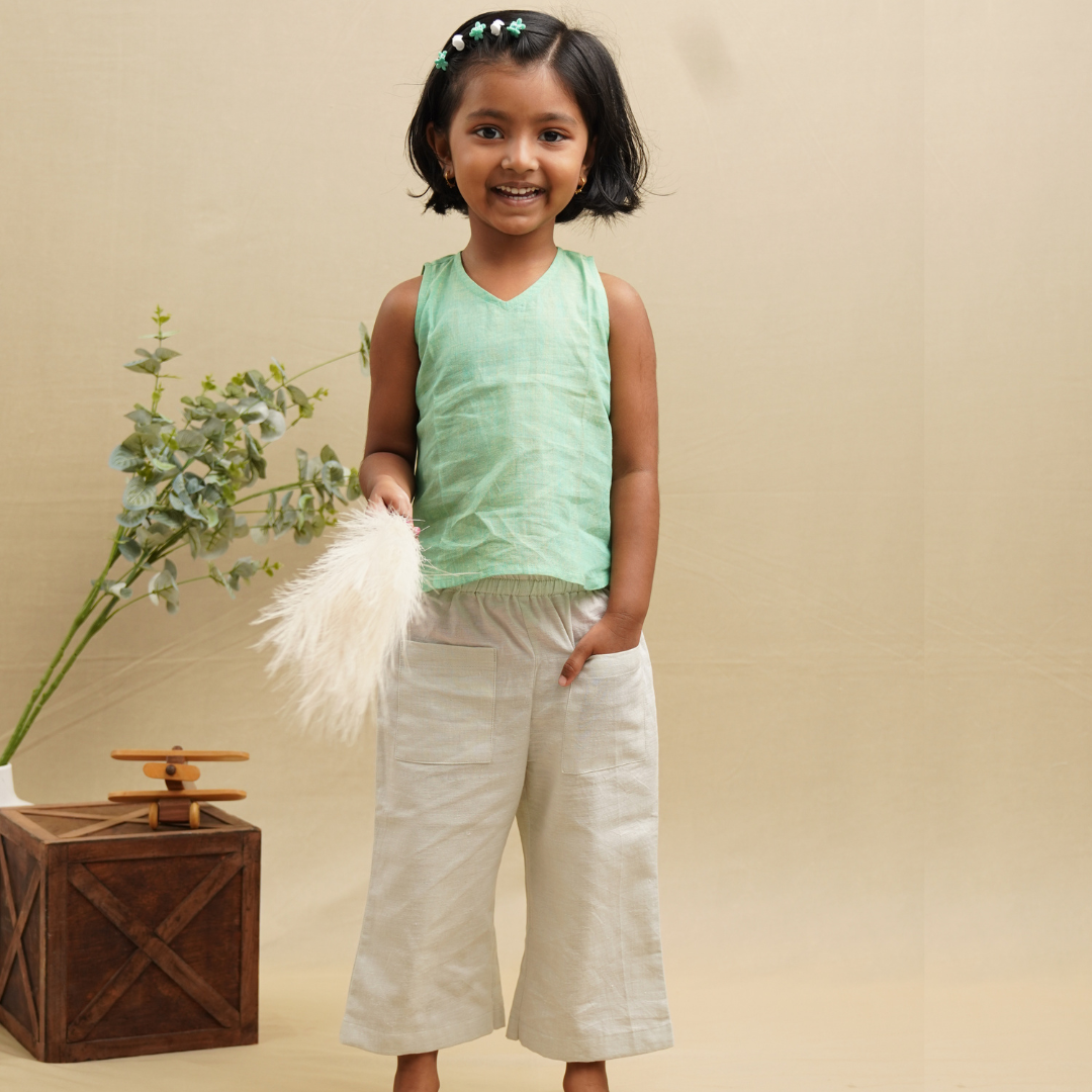 A girl wearing cotton pants with a green sleeveless top in Khadi fabric