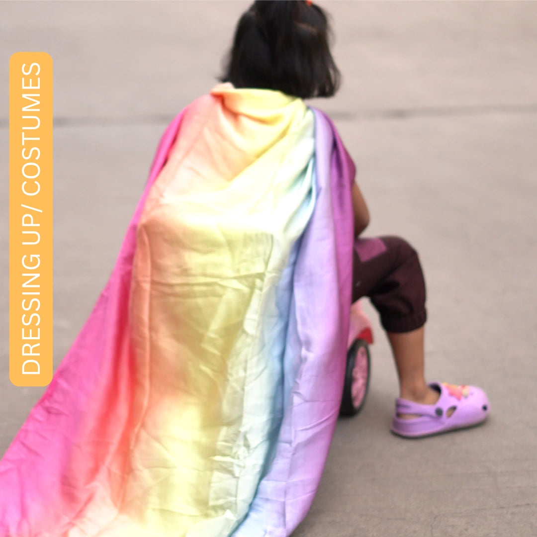 Child dressed in a soft rainbow semi-giant playsilk cape while engaging in pretend costume and role play