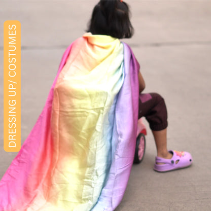 Child dressed in a soft rainbow semi-giant playsilk cape while engaging in pretend costume and role play