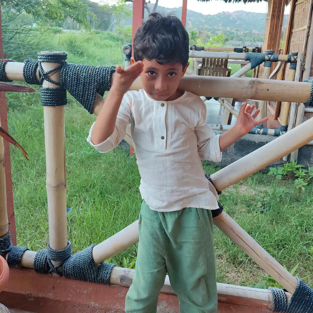 Child wearing cotton shirt and trouser standing on a wooden structure 