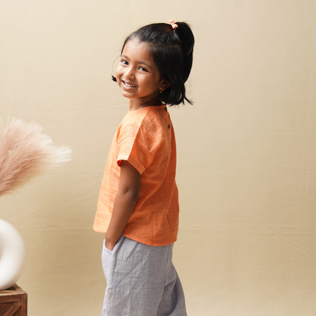 Girl wearing cotton top made from khadi and smiling against a beige background