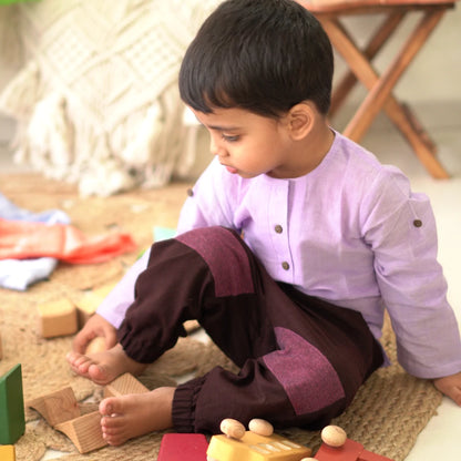 Child sitting and playing indoors while wearing comfortable khadi unisex joggers with reinforced knee patches