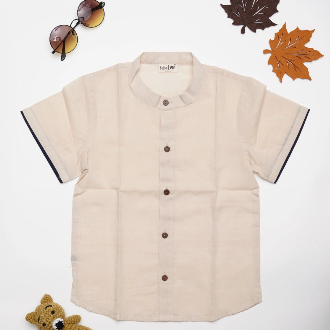 Beige short-sleeve shirt with black trim on a white background, surrounded by autumn-themed items.