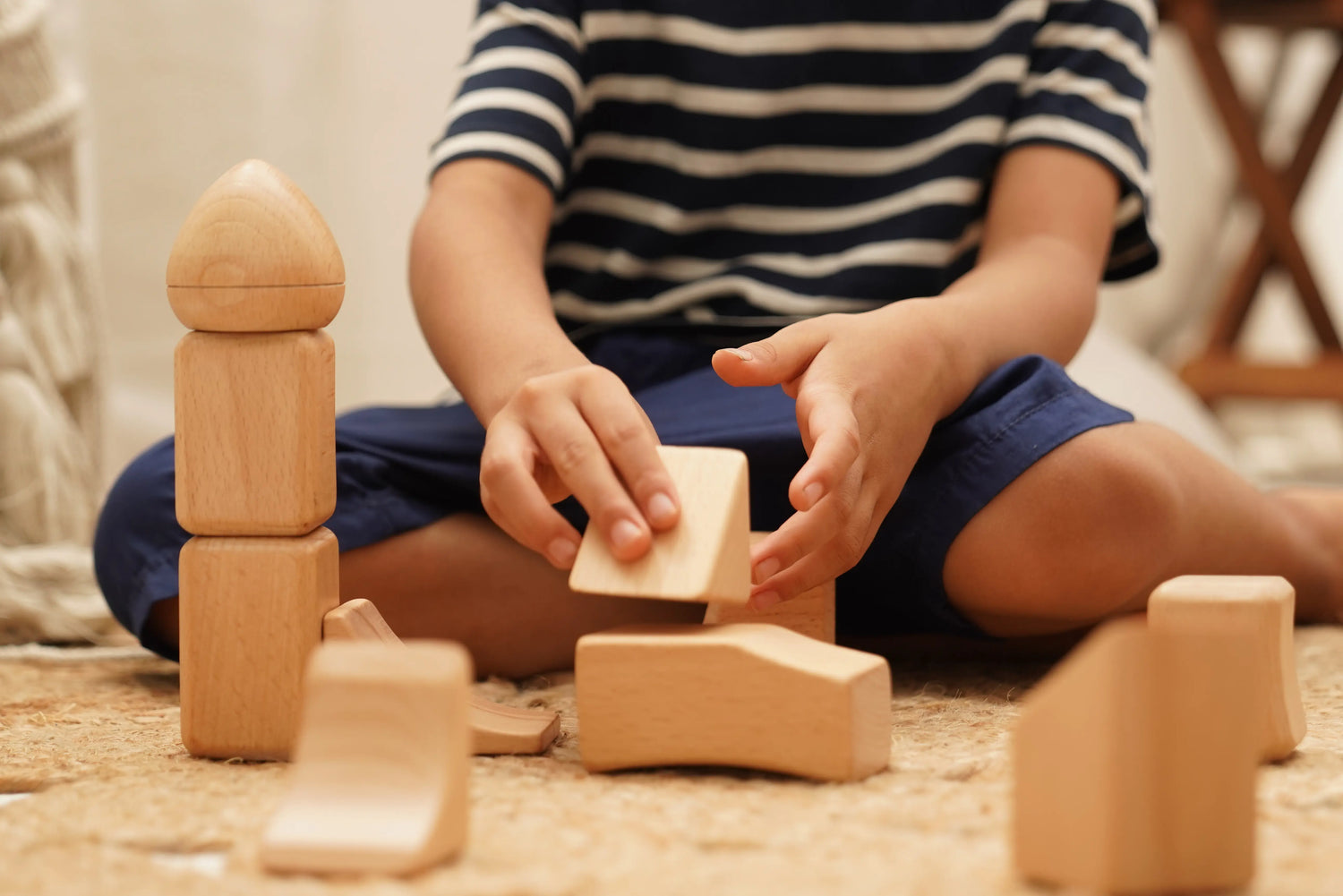 Child playing with wooden blocks on a carpeted floor