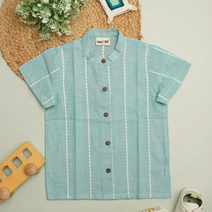 Product flat lay of a mint green unisex cotton shirt for kids with white woven stripes, wooden buttons, and breathable handloom fabric