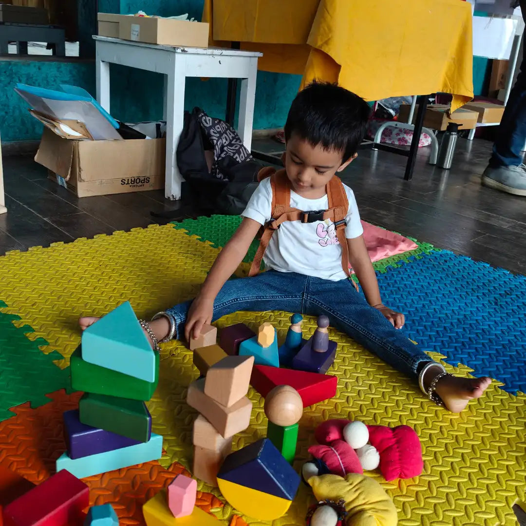 Child playing with colorful building blocks on a mat in an indoor setting