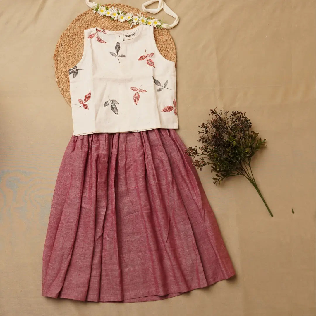 White sleeveless top with floral patterns and a pink skirt on a beige background
