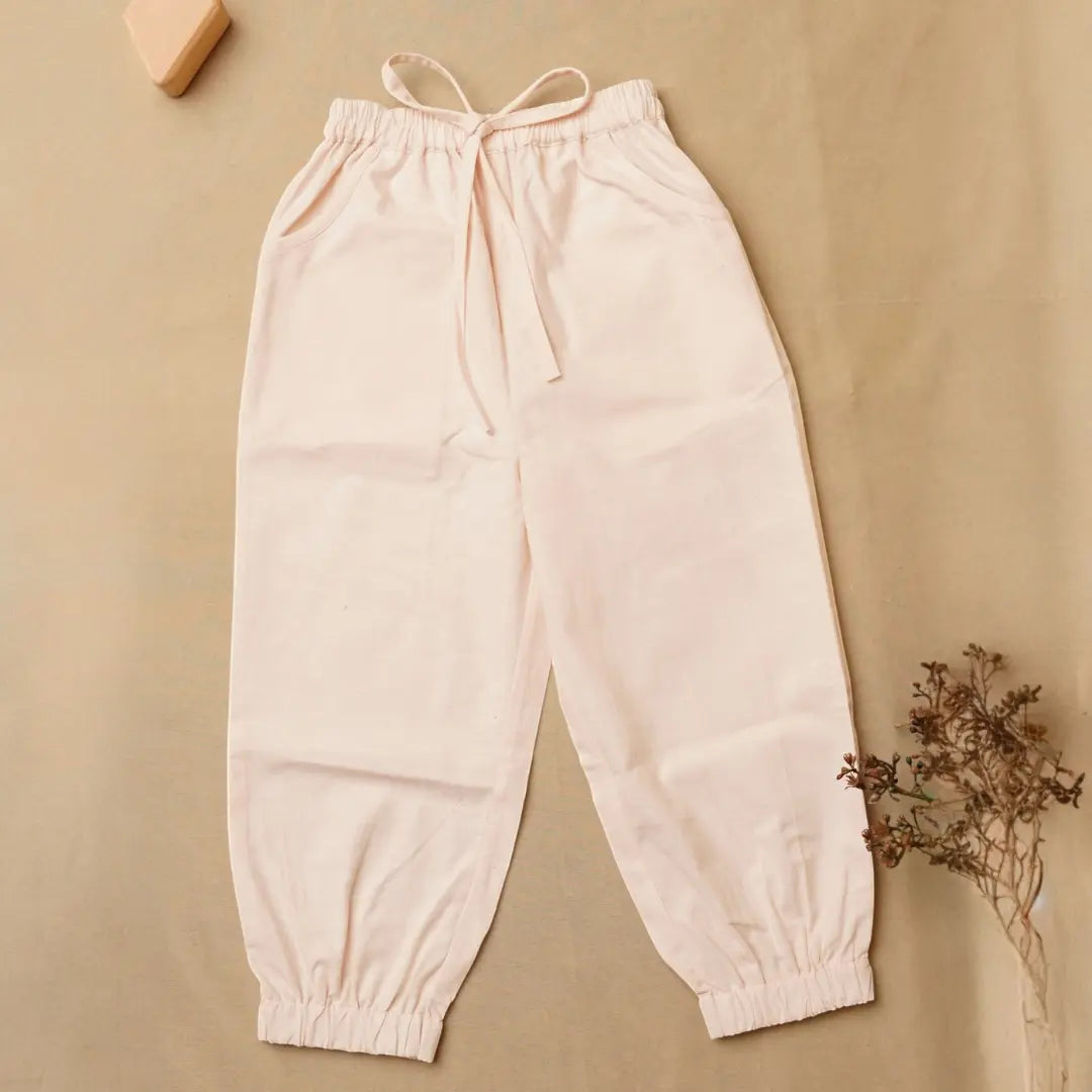 A pair of light blush pink jogger pants with an elastic drawstring waist and elastic cuffs