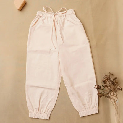 A pair of light blush pink jogger pants with an elastic drawstring waist and elastic cuffs