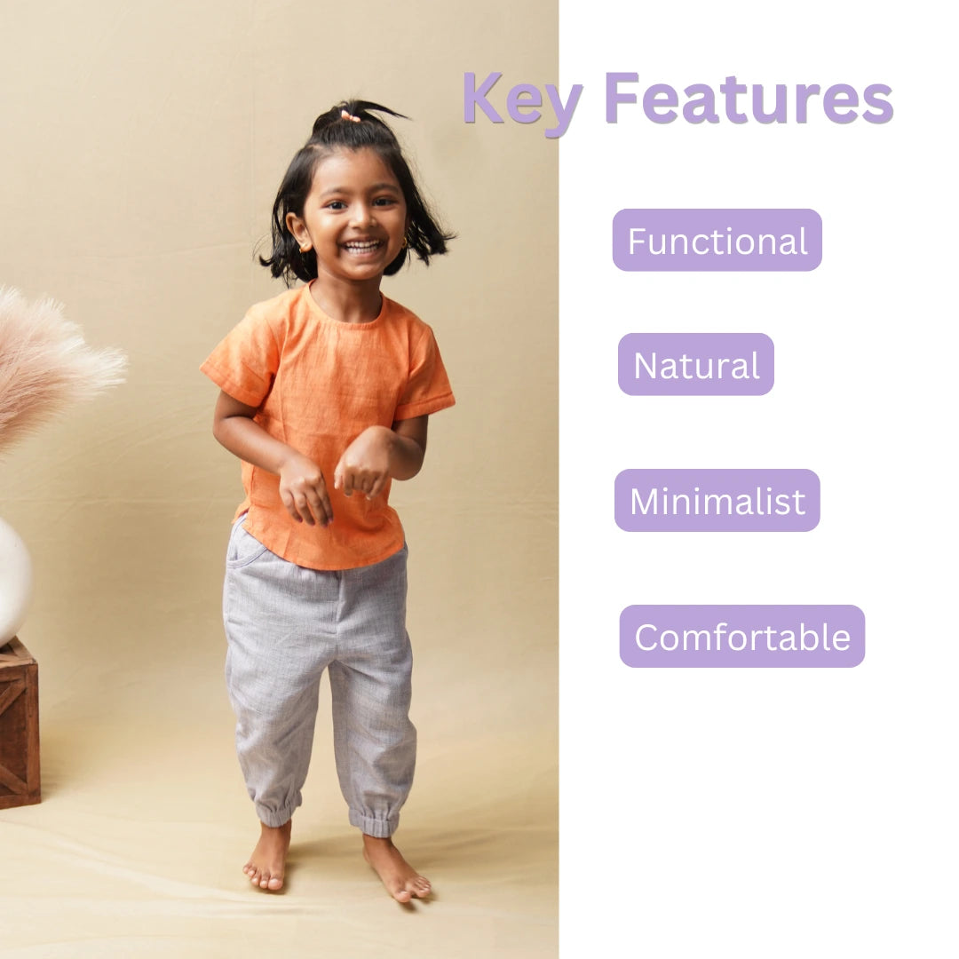 Smiling girl in light purple cotton joggers and orange top with key features: functional, natural, minimalist, comfortable