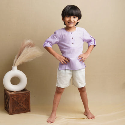 Child in light purple cotton kurta with roll-up sleeves and white shorts, hands on hips