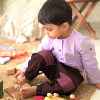 Toddler in a light purple full sleeve cotton kurta playing with wooden blocks on a jute rug