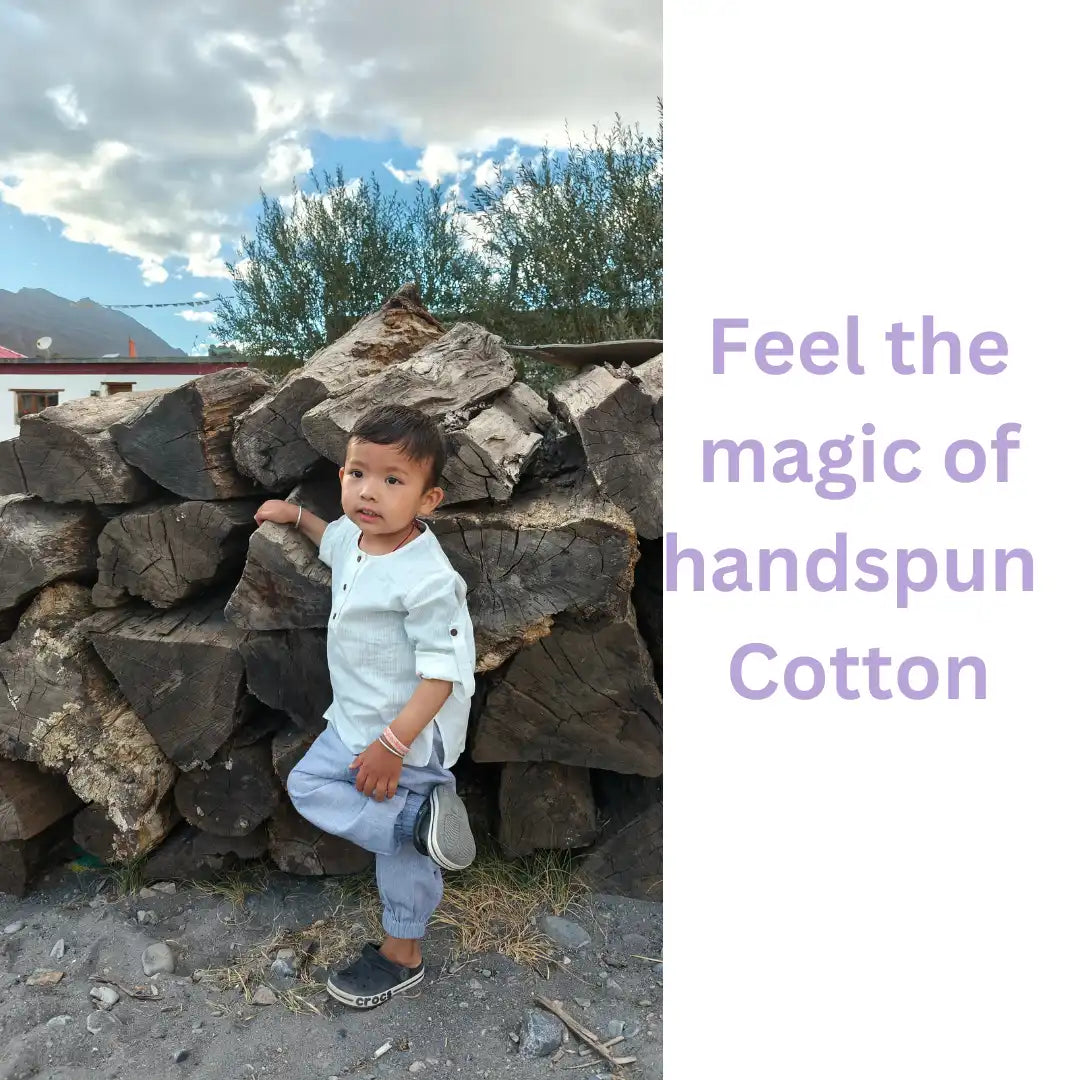 Toddler in light purple handspun cotton joggers playing by a woodpile outdoors