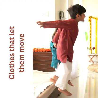 Boy in a maroon kurta and white pajama jumping off a bed with arms outstretched, with the text clothes that let them move