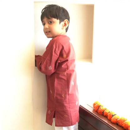 Boy in a maroon handloom cotton kurta with gold and white woven motifs, seen from the side