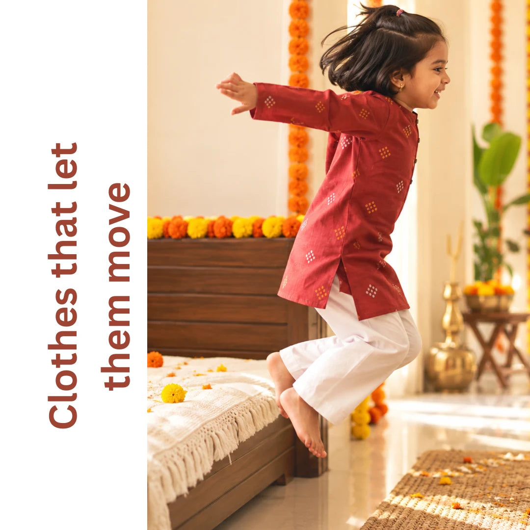 Girl in a maroon kurta and white pajama jumping off a bed, with the text clothes that let them move