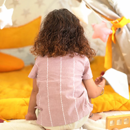 Back view of a child in a mauve handloom cotton shirt with white woven raindrop stripes running down the back
