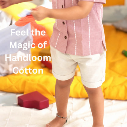 Close-up of a mauve handloom cotton shirt with wooden buttons worn with beige cuffed shorts, with the text feel the magic of handloom cotton