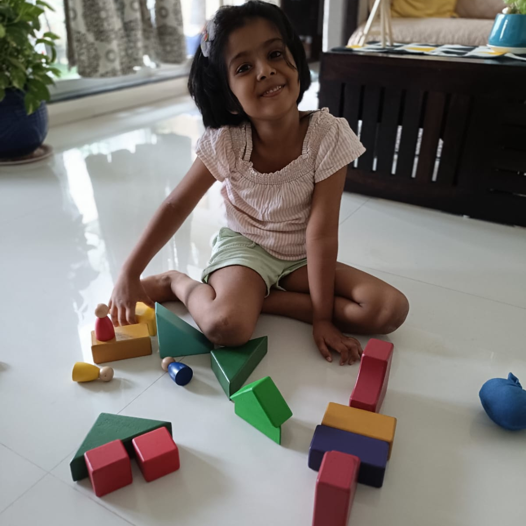 Child playing with colorful wooden blocks on a white floor