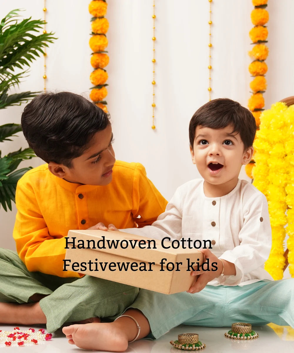 Two boys in handwoven cotton kurtas, one mustard and one white, sitting among marigold garlands, with the text handwoven cotton festivewear for kids